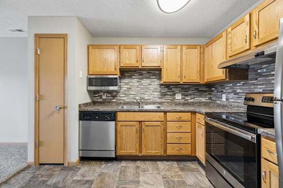 A kitchen with wooden cabinets and a stone backsplash.