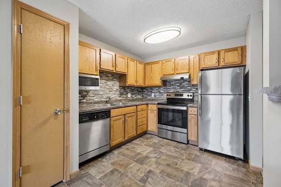 A kitchen with wooden cabinets and stainless steel applicances.