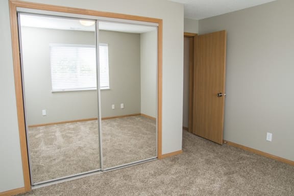 a bedroom with a mirrored closet and a window