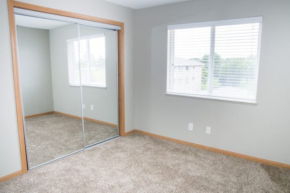 an empty bedroom with a mirror and a window