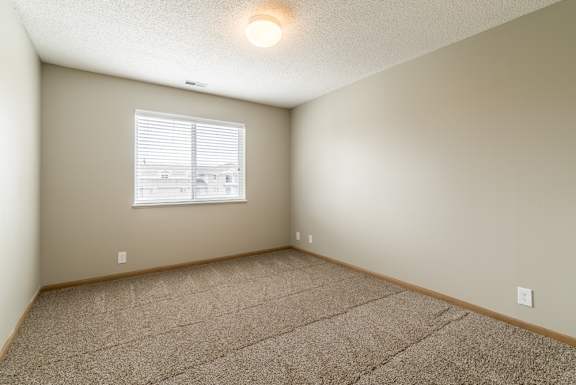 a bedroom with a carpeted floor and a window with blinds