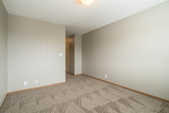 a bedroom with a carpeted floor and a hallway to the attached bathroom