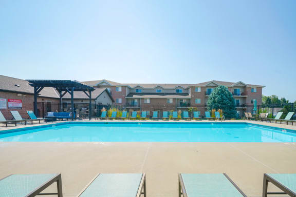 a rectangular pool with lounge seating in front of Highland View Apartments