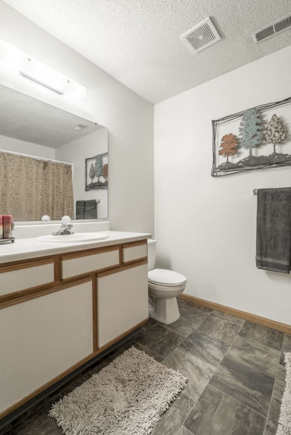 Bathroom in non-renovated unit with white and wood cabinetry