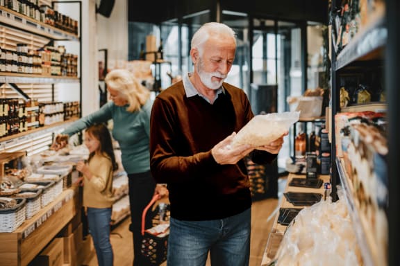 an older man looking at a piece of paper in a grocery store