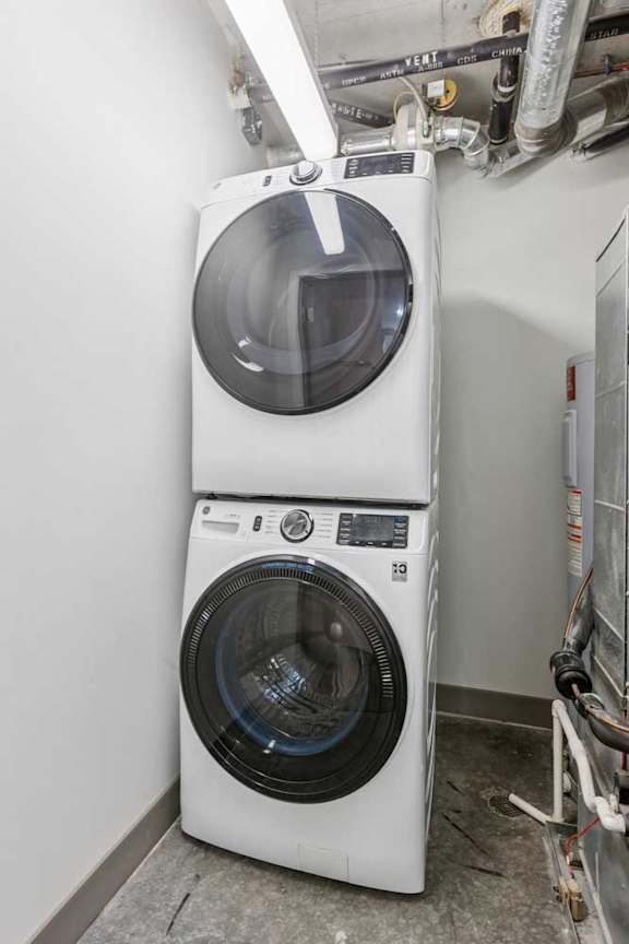 A stacked, full-sized washer and dryer in a laundry closet.