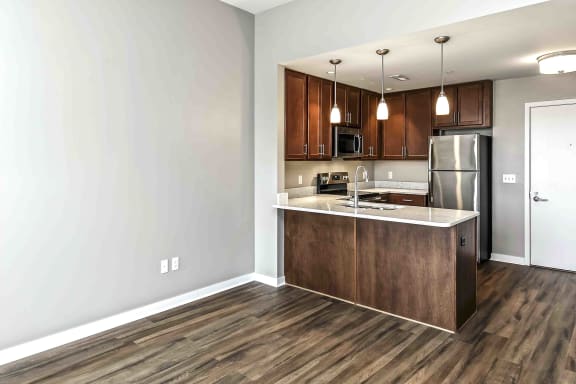 U-shaped kitchen with warm dark brown cabinets and pendant lighting