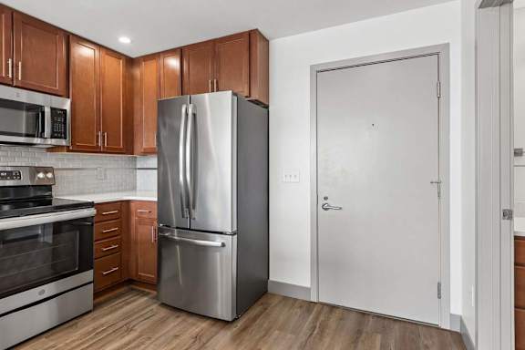 A modern kitchen with a stainless steel refrigerator and wooden cabinets.