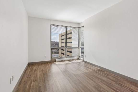 A room with wooden floors and a large window overlooking a building.