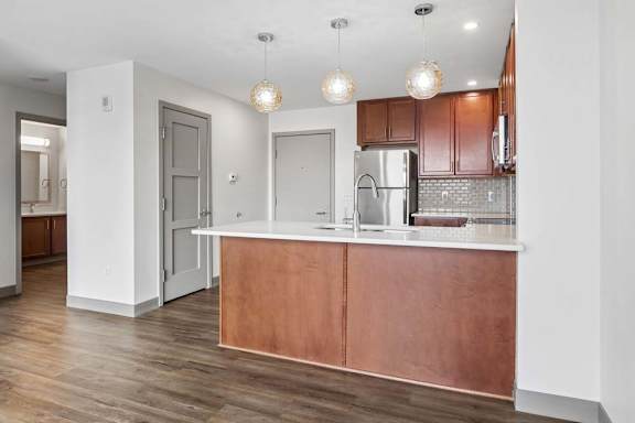 A kitchen with a refrigerator, sink, and wooden cabinets.
