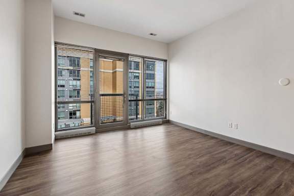 A room with a wooden floor and a view of a city through a window.