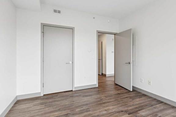 A bedroom with hardwood-style flooring and a walk-in closet.