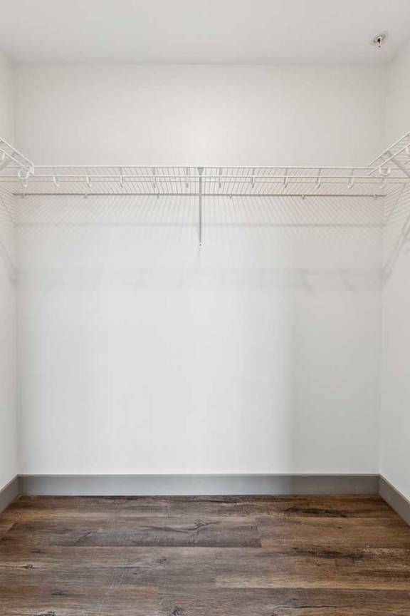 A walk-in closet with a built-in wire shelf.
