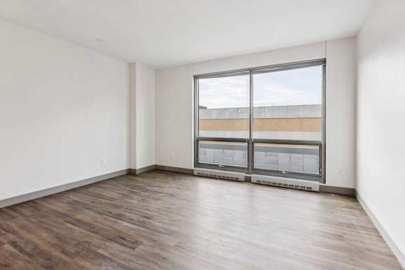 A living room with hardwood-style flooring and a floor-to-ceiling window.