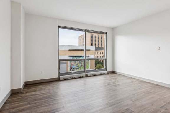 A living room with hardwood-style flooring and a floor-to-ceiling window.