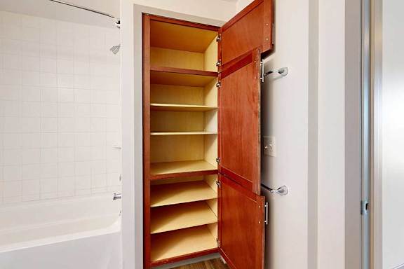 A wooden linen closet with built-in shelves in the primary bathroom.