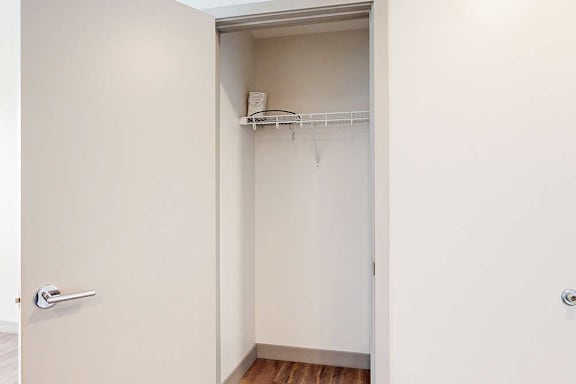 A hallway coat closet with a built-in wire shelf.