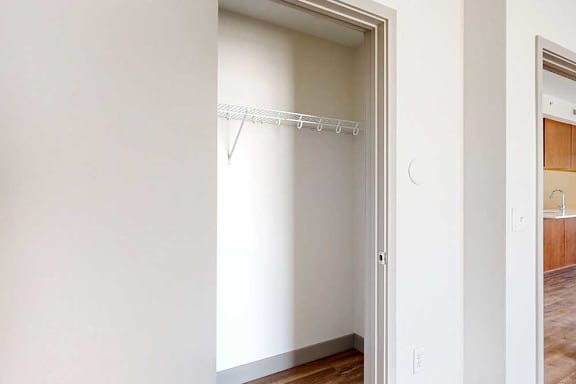 A wide walk-in closet with a built-in wire shelf.