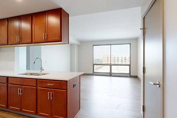 A kitchen with warm wooden cabinets in front of a spacious living room.
