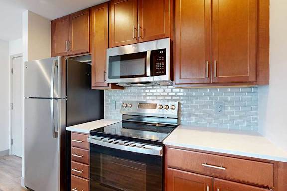 A modern kitchen with a stainless steel range, refrigerator, and microwave.