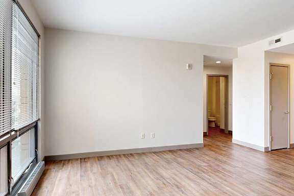 A living room with hardwood-style flooring and a floor-to-ceiling window.