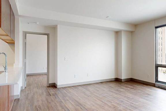 A living room with hardwood-style flooring and a floor-to-ceiling window.
