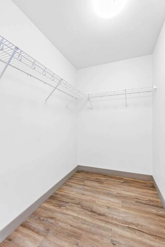 A bedroom with a white wall and a wooden floor.