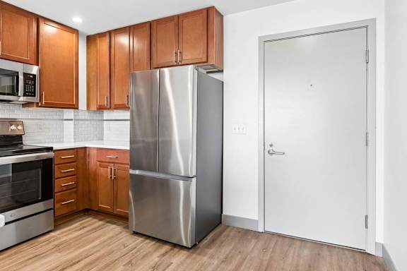 A kitchen with a refrigerator, oven, and microwave.
