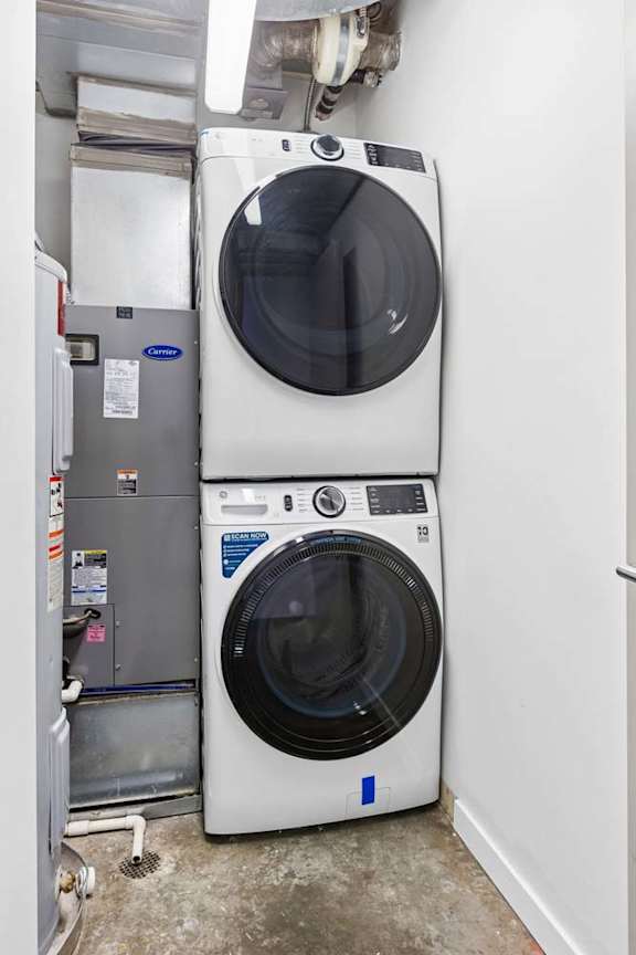 A stacked washing machine is in a small room