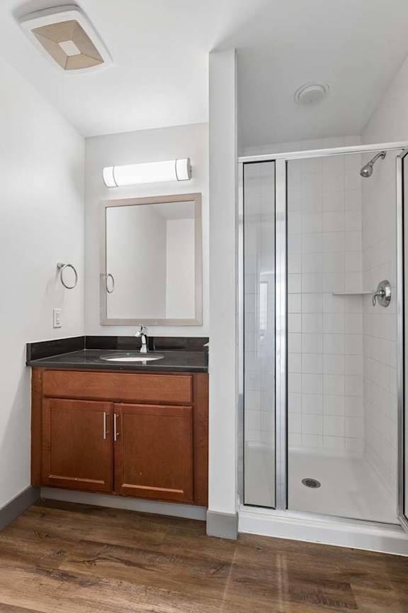 A bathroom with a sink, mirror, and shower.