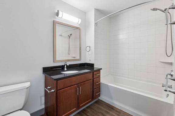 A bathroom with a white tub, sink, and a mirror.