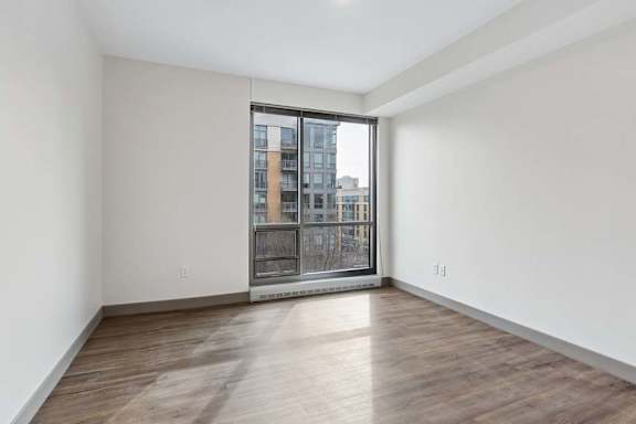 A room with a large window and wooden flooring.