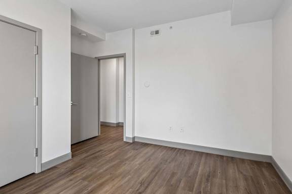 A room with white walls and wooden flooring with two doors.
