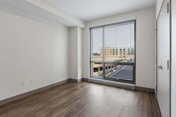 A room with a view of a parking lot through a window.