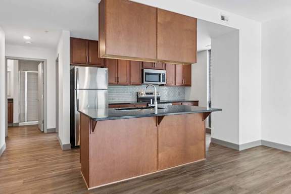A kitchen with a refrigerator, microwave, and stove top oven.