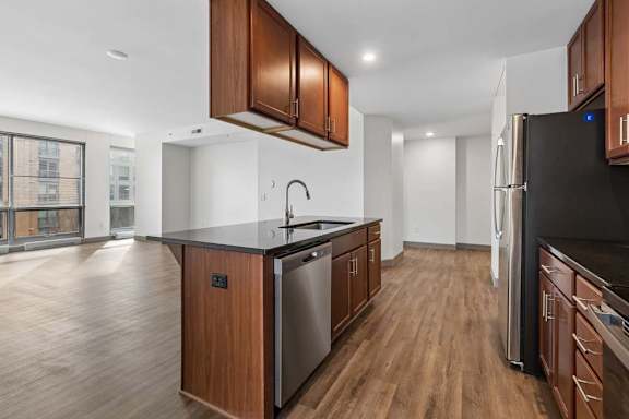 A kitchen with wooden cabinets and a black fridge.