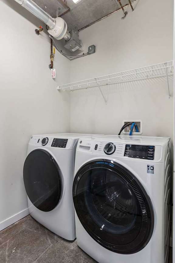 Two white front load washing machines in a laundry room.