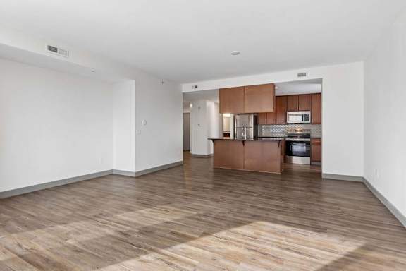 A spacious room with a kitchen area in the background.