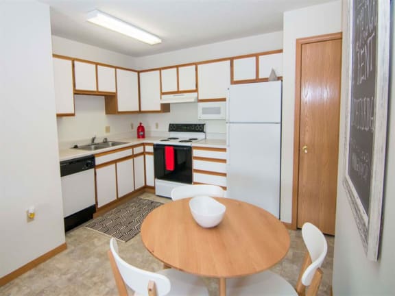 L-shaped kitchen with white cabinets and small dining area
