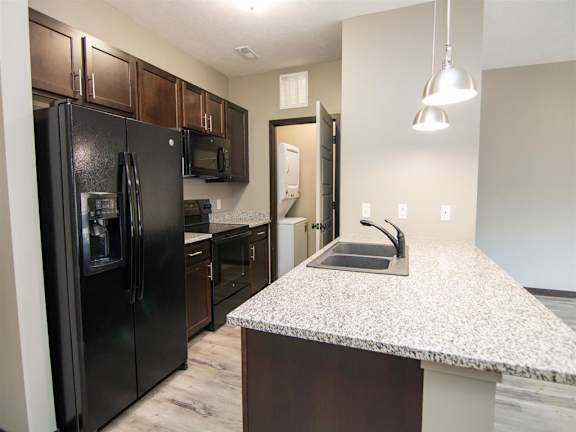 Gallery style kitchen with dark brown cabinets and black appliances