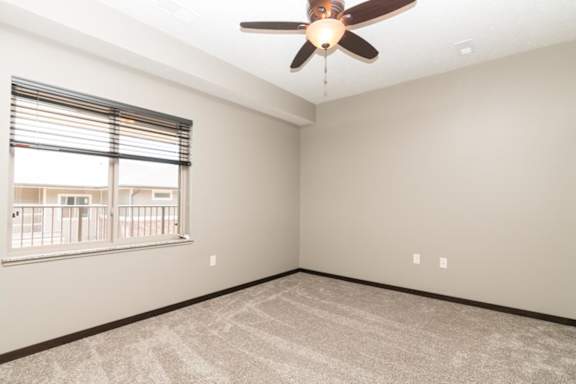 A room with a ceiling fan and a window with blinds.