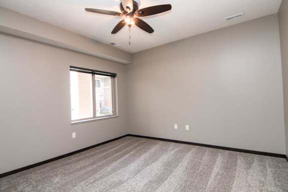 A room with a ceiling fan and carpeted floor.