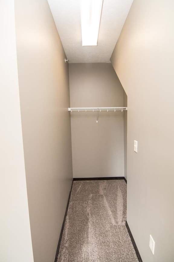 A long, narrow closet with a shelf and a light on the ceiling.