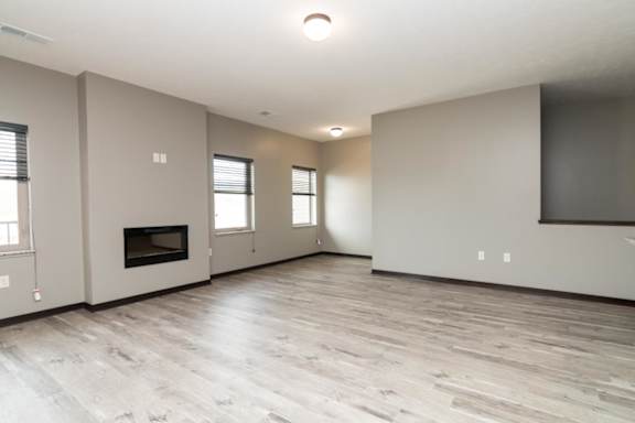 A spacious living room with a fireplace and and light brown floors
