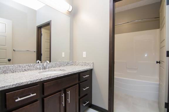 A bathroom with a sink, mirror, and bathtub.