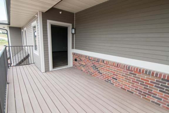 A deck with a brick wall and a door.