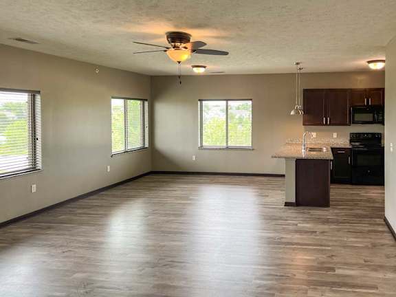 a spacious living room with a kitchen area in the background