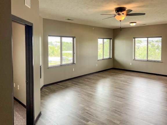 a living room with several large windows and hardwood flooring