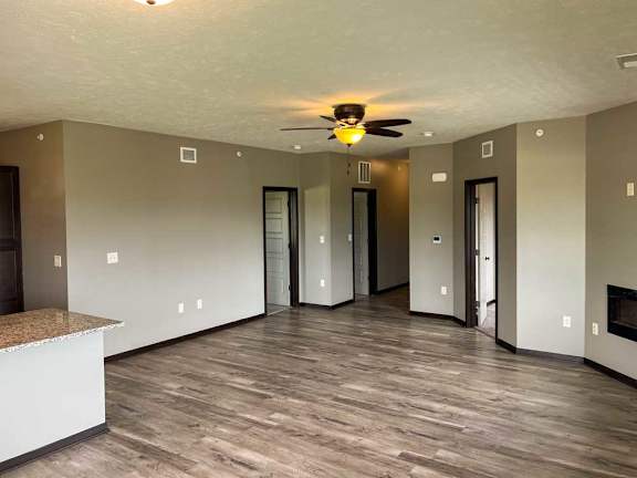 a spacious living room with hardwood flooring, a ceiling fan, and a fireplace