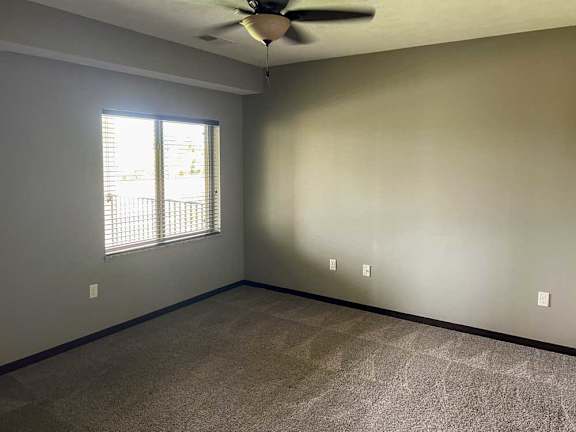 a bedroom with a ceiling fan, carpeted flooring, and a large window